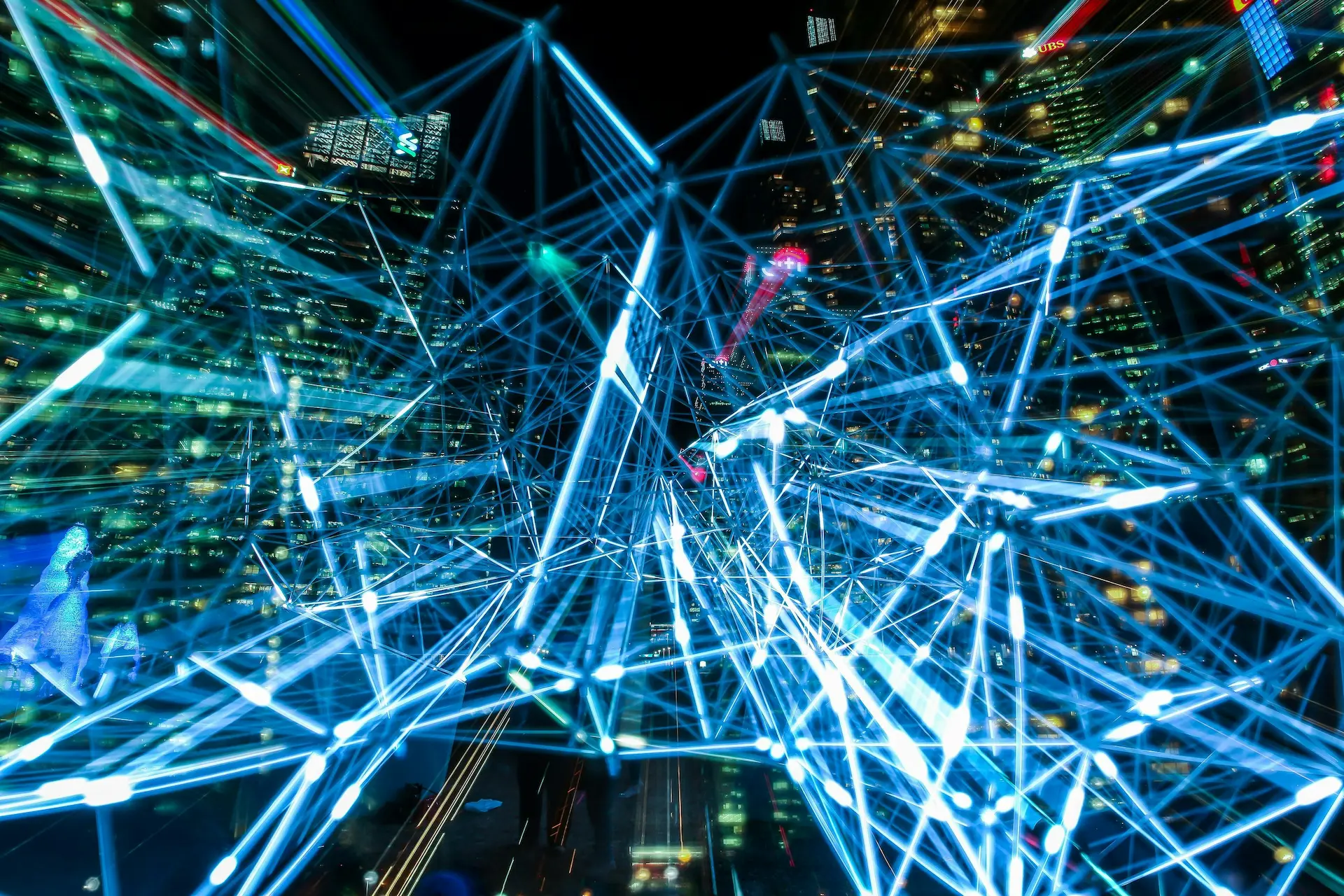 A city skyline at night overlaid with abstract lines of light representing connected systems