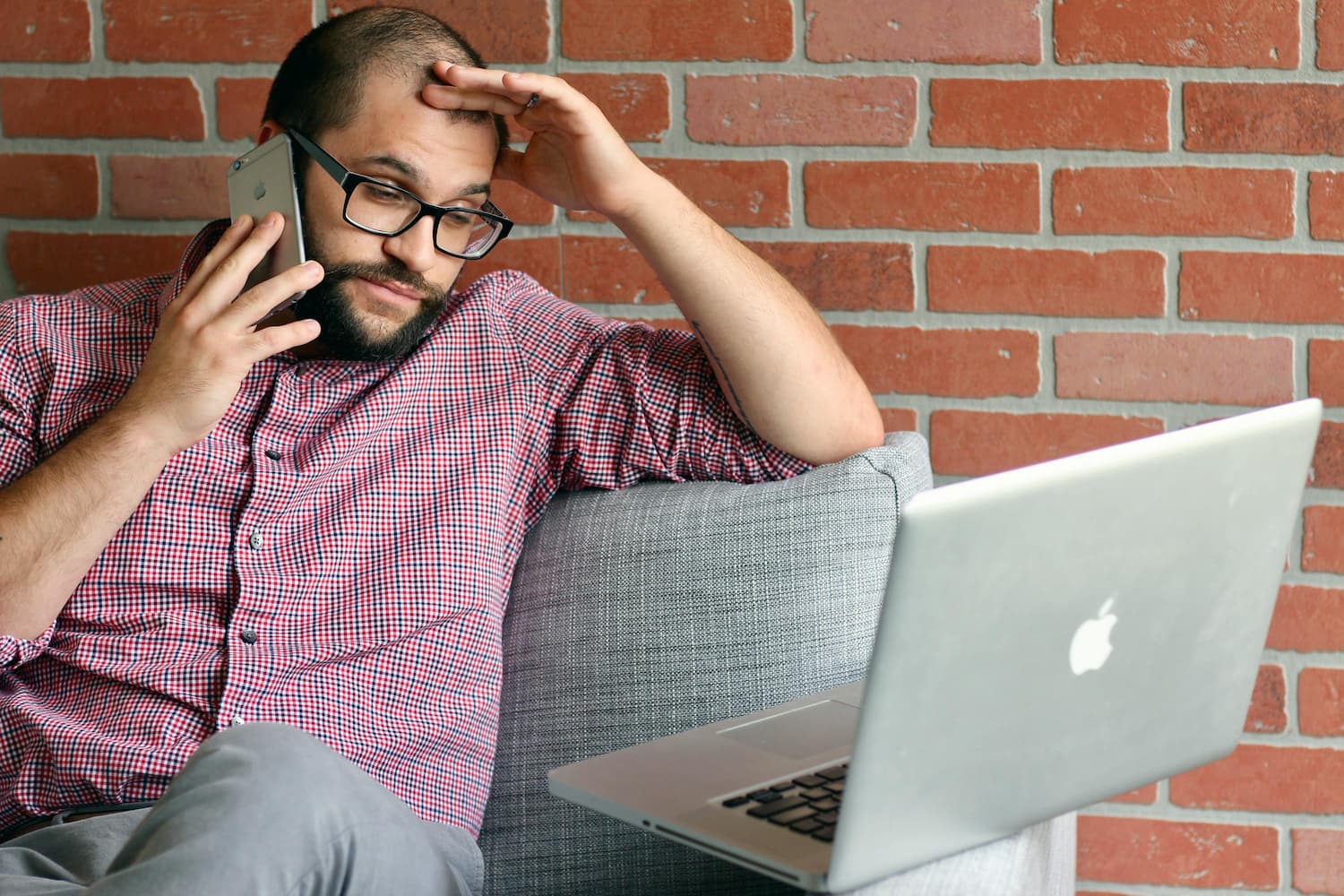 A man on the phone looking frustrated while checking his laptop
